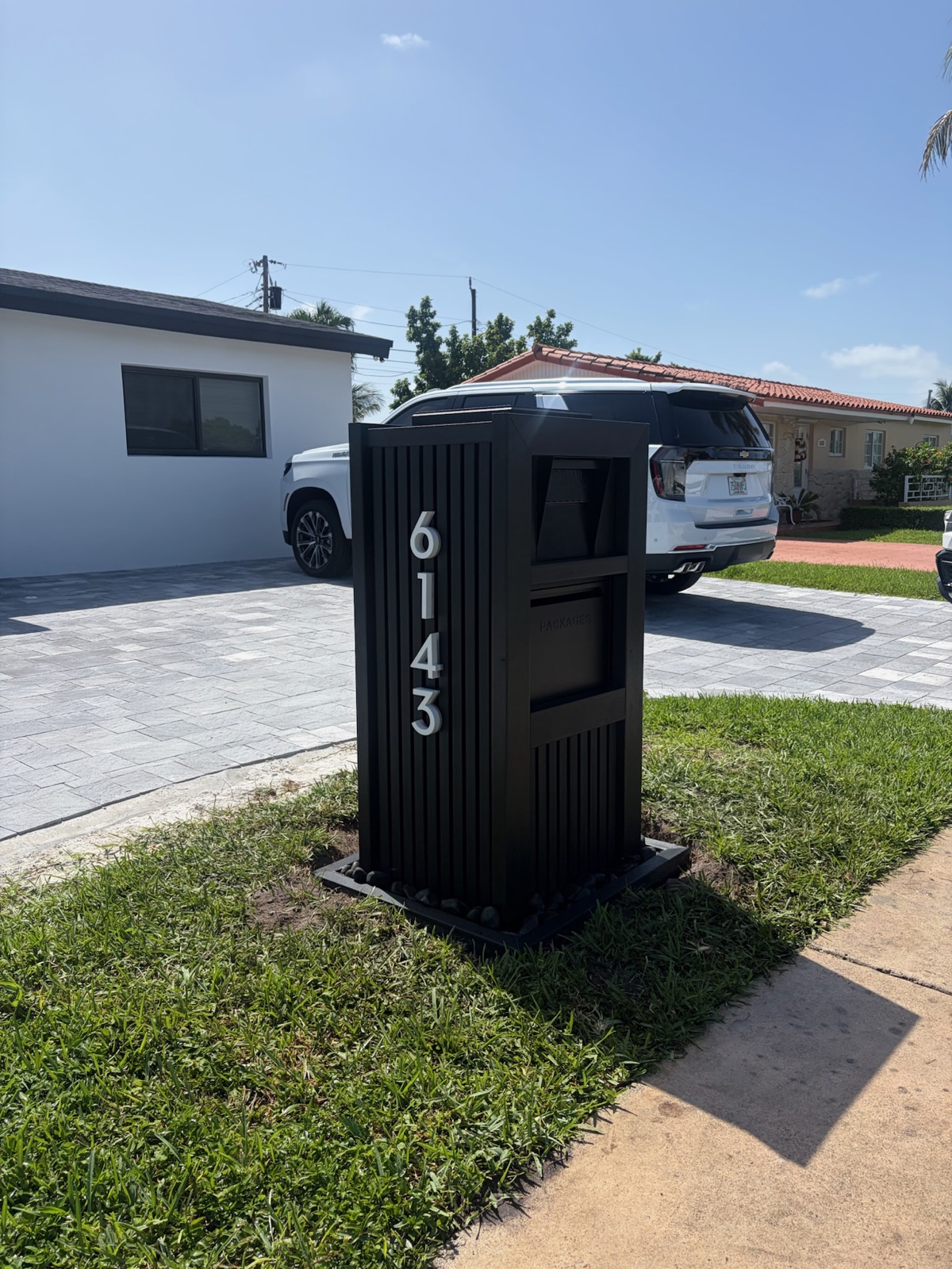 A modern rust-proof mailbox standing at the curb of a waterfront coastal home