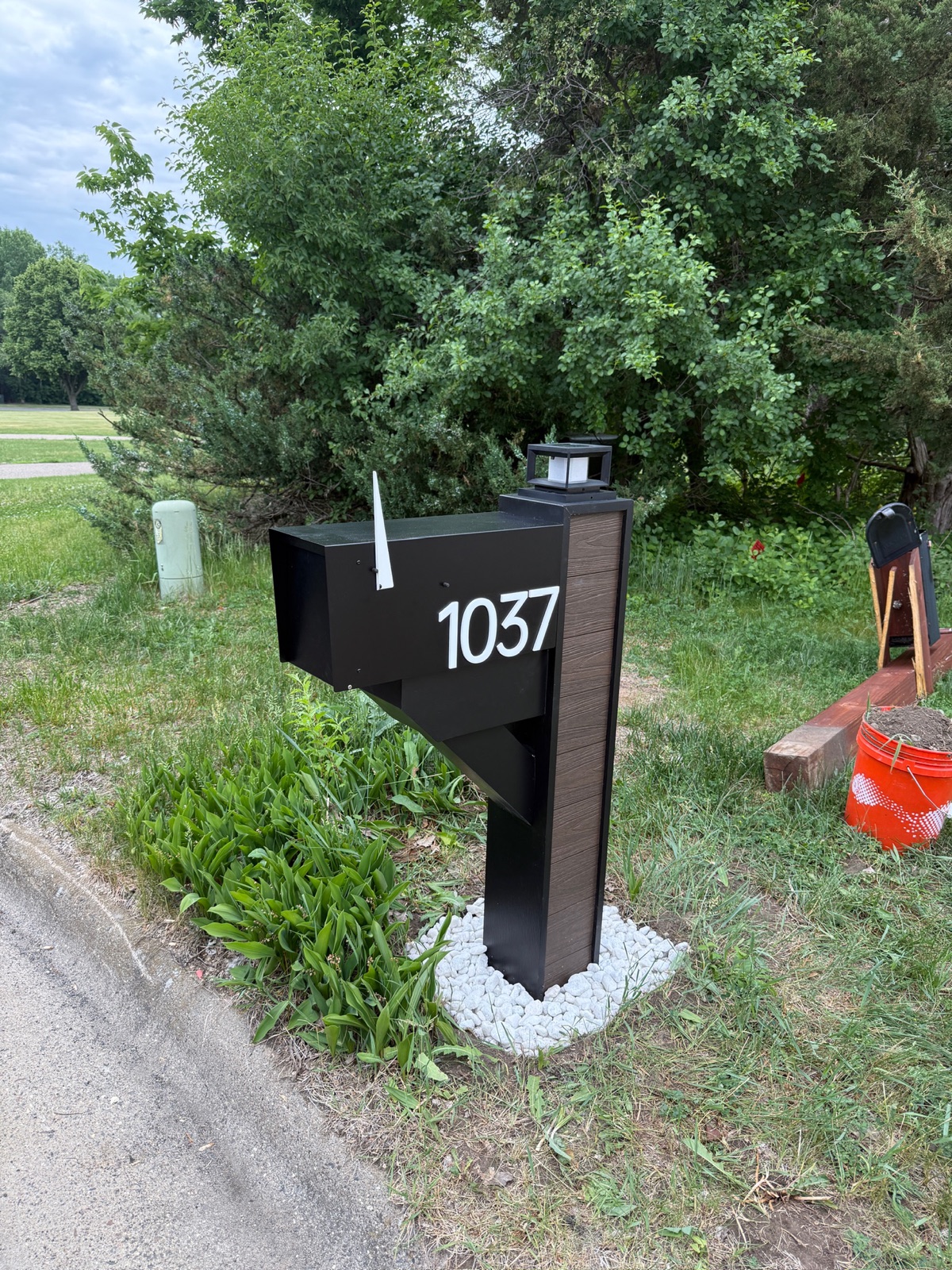 A design mockup of a custom community mailbox with house numbers, prepared for board approval