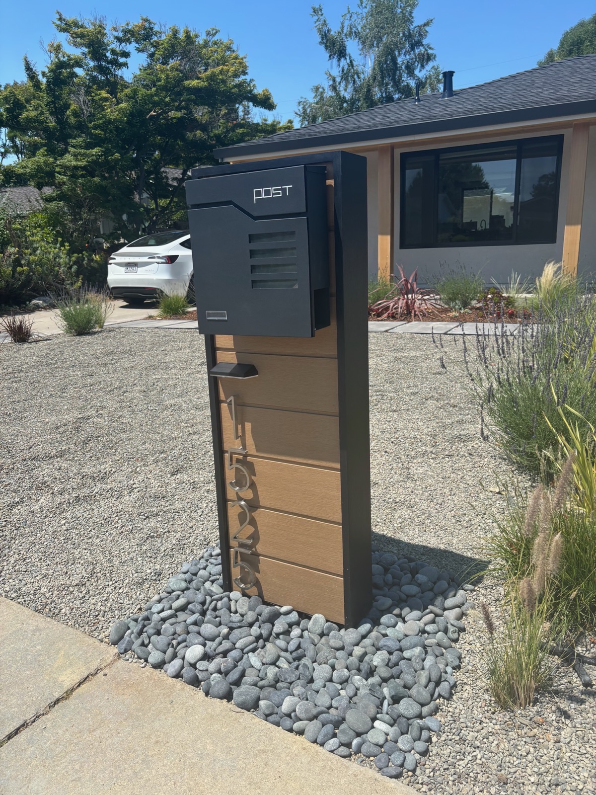 A custom mailbox and post set at a community curb with a finished rock bed at the base