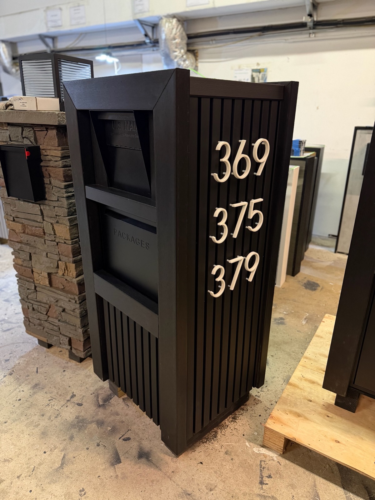 A modern duplex mailbox with two separate locking compartments mounted at the curb of a two-family home