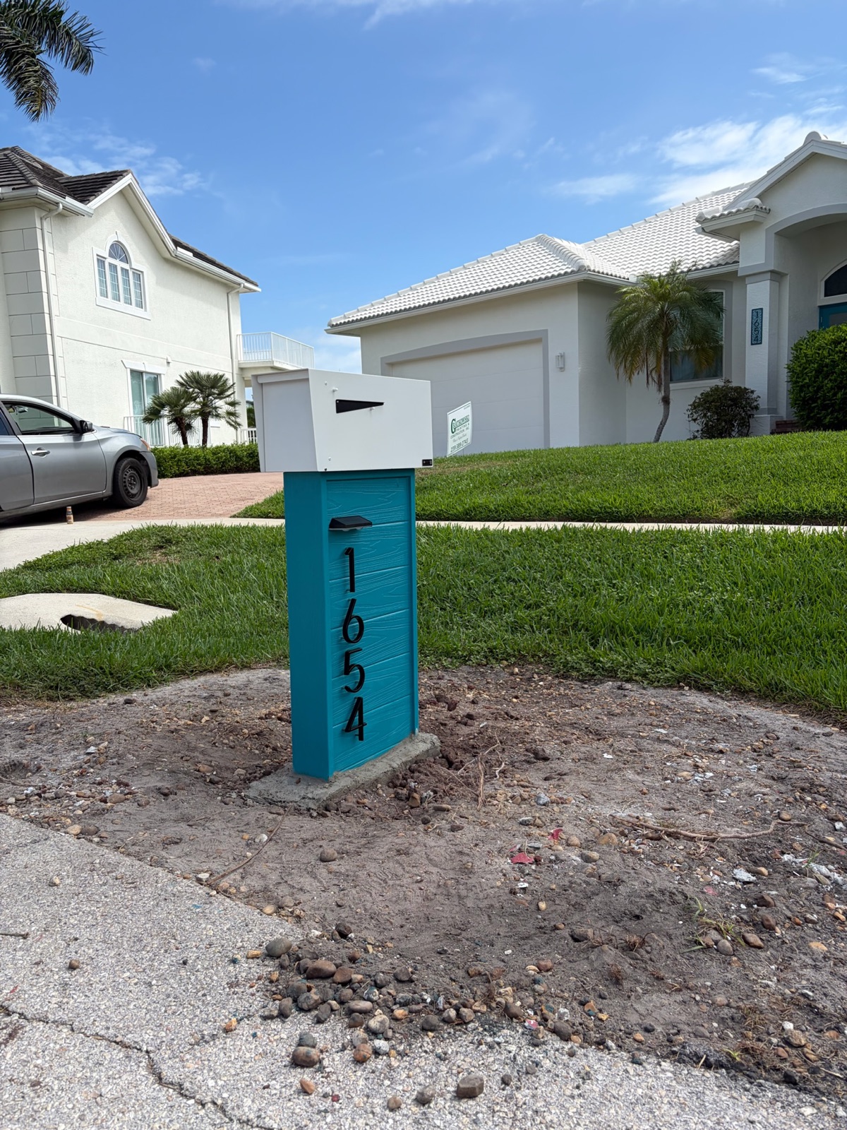 A custom community mailbox and post set at the curb with a finished rock bed