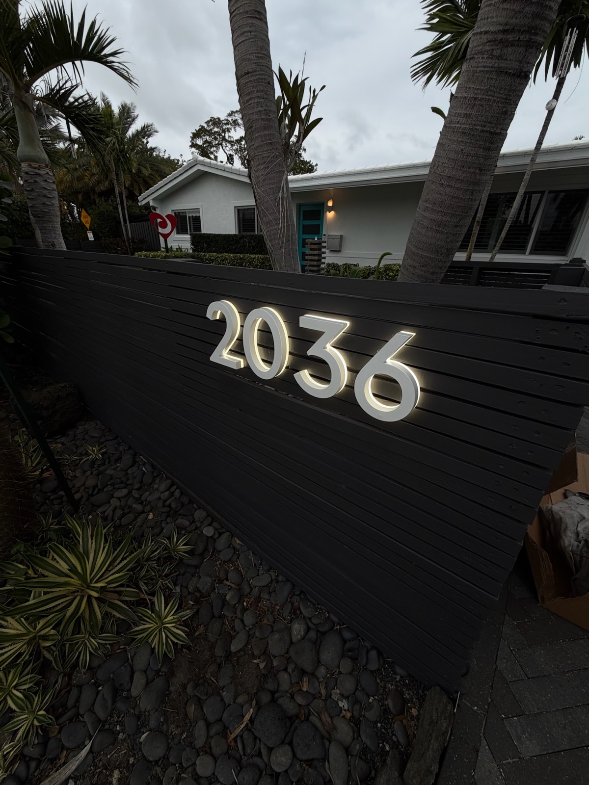 A faux stone pillar mailbox set at the curb in front of a home