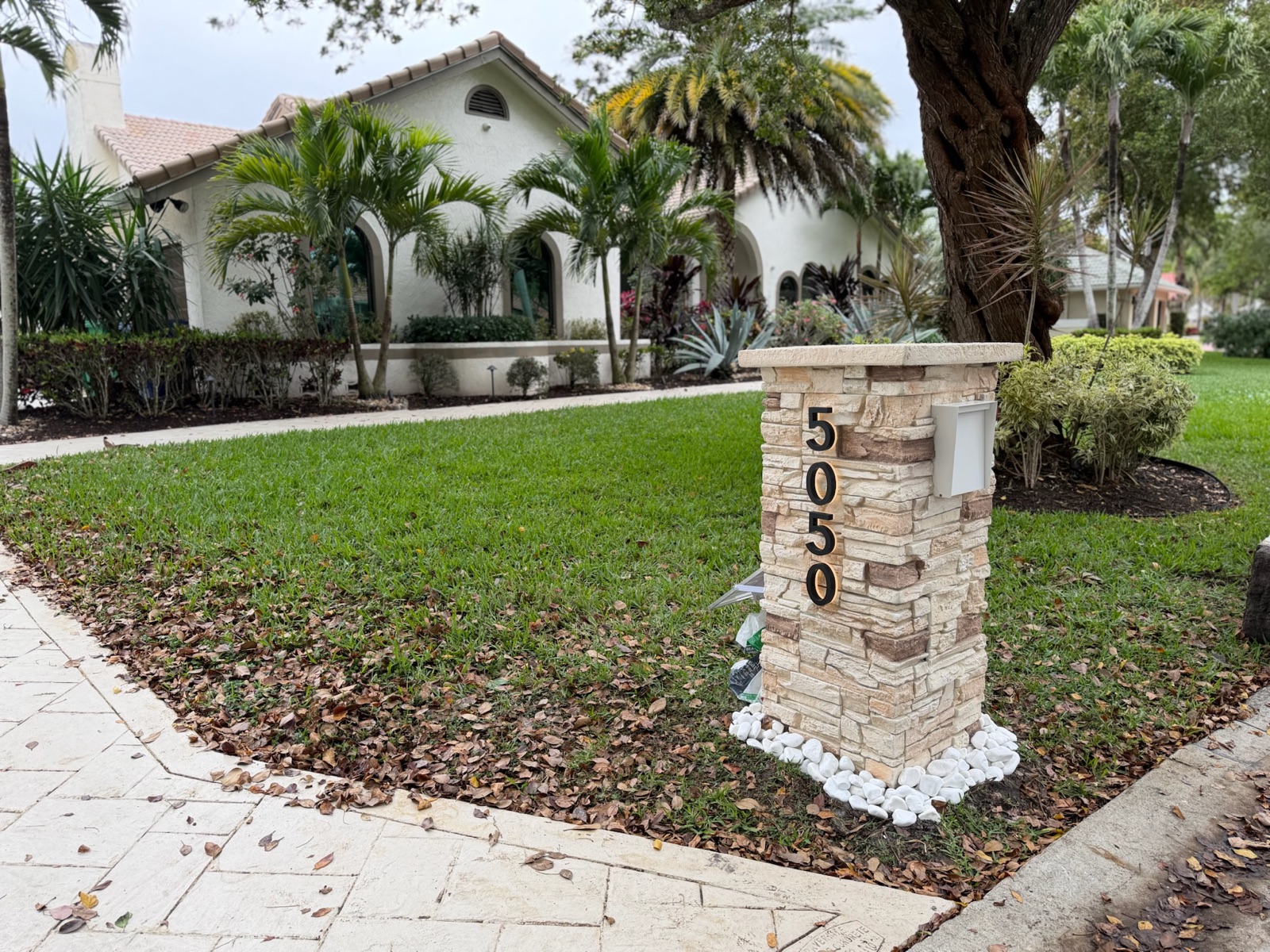 A cast faux marble pillar mailbox shown close up at the curb