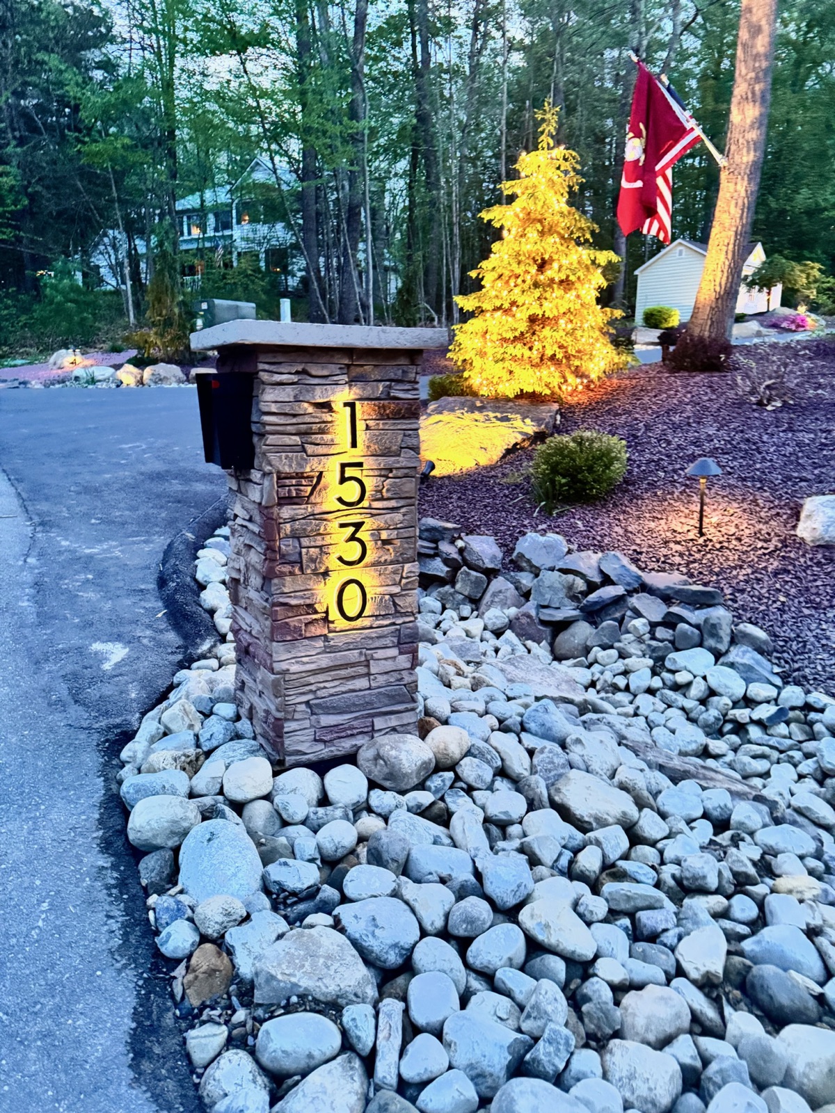 A halo-lit custom address plaque glowing against a wall at dusk