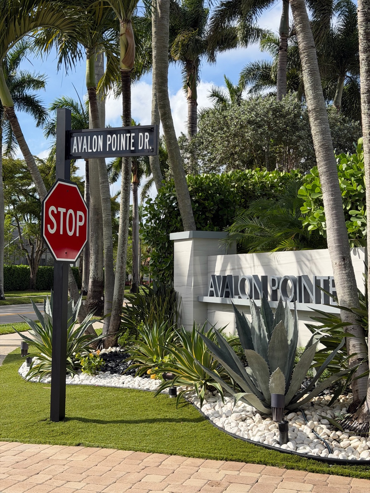 A lit address plaque mounted on a stone and marble entry column beside a driveway