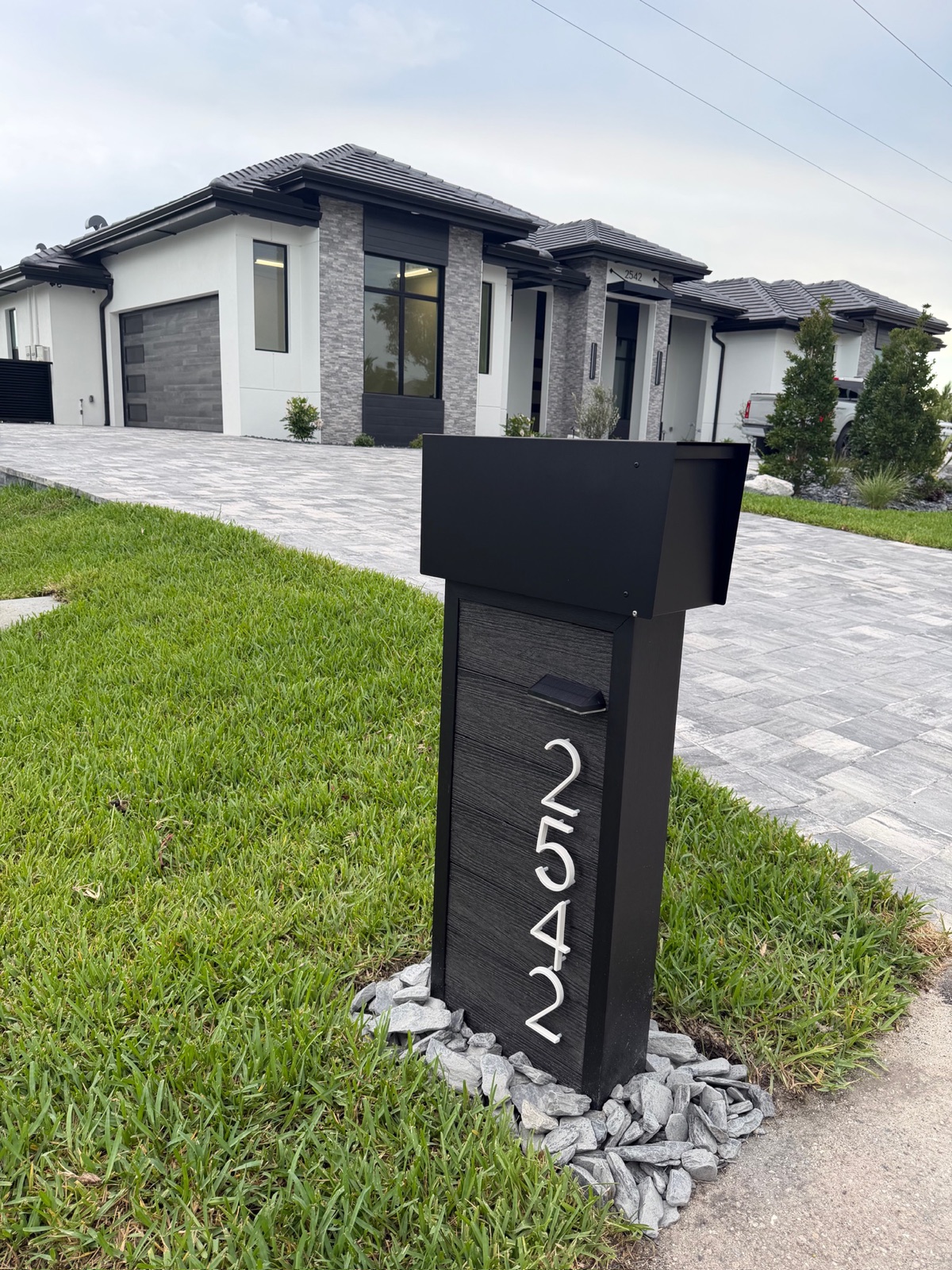 Close view of custom house numbers applied to a community mailbox, showing numeral size, typeface, and contrast against the box color