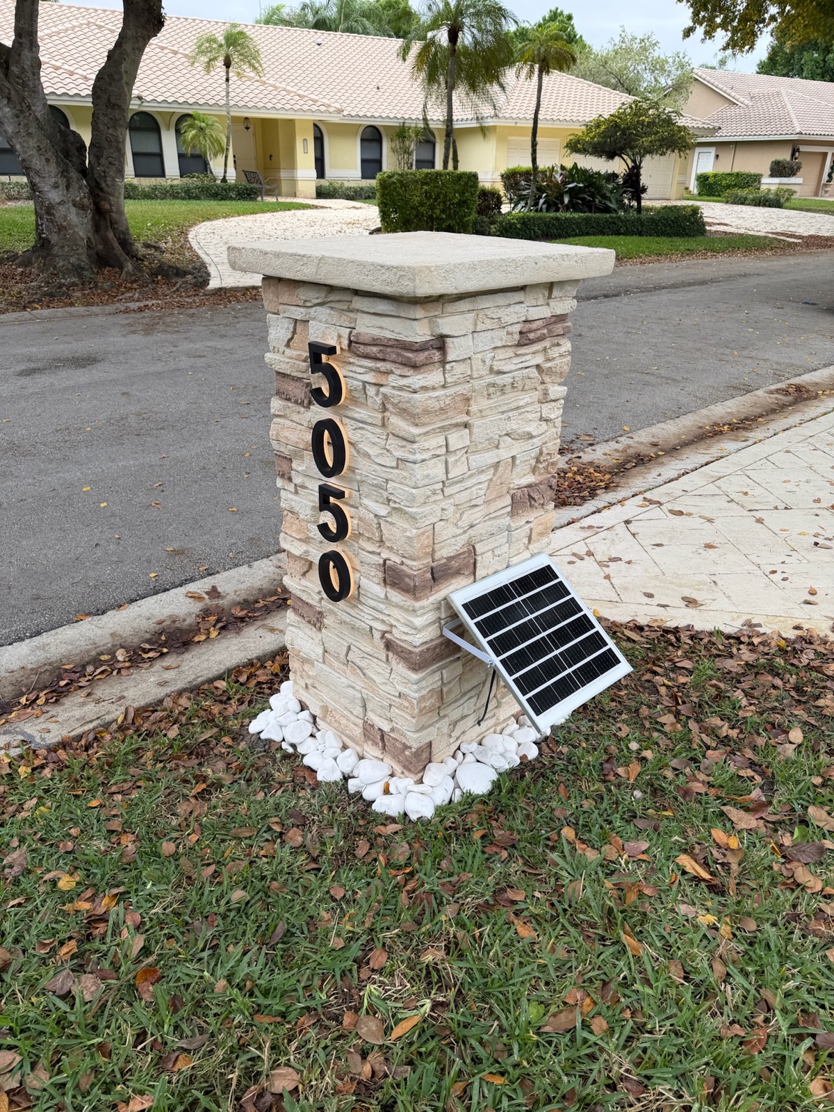 A slim contemporary pillar mailbox in a matte custom color beside a modern home entry