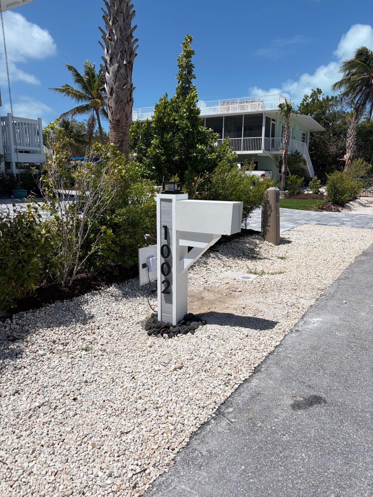 A black Slatline aluminum mailbox set on a post at the curb of a Houston-area home