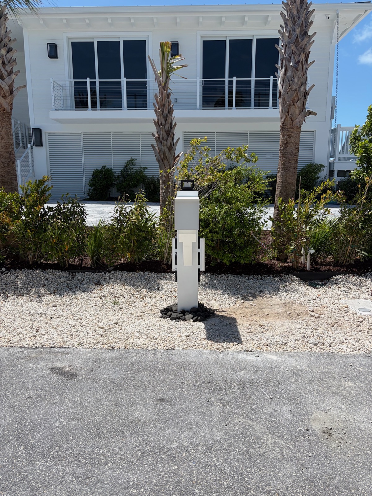 A Modern Farmhouse composite mailbox in a walnut finish mounted on a post