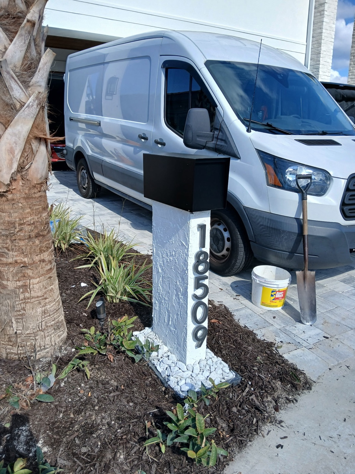 A black and white Slatline aluminum mailbox set at the curb of a coastal home