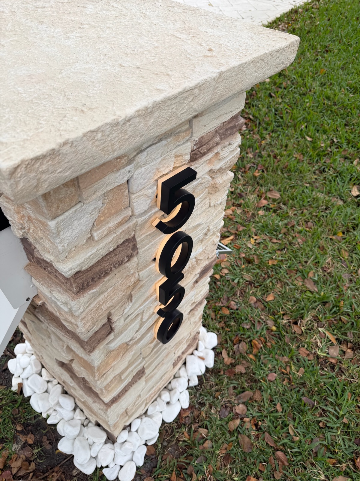 A faux stucco pillar mailbox shown in a warm green-toned finish