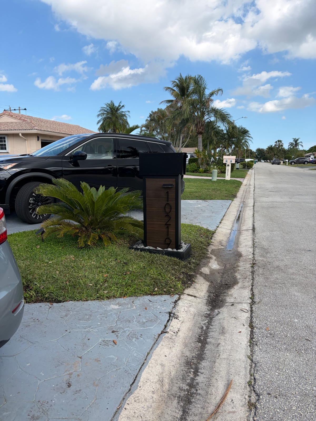 A white and black modern farmhouse composite mailbox installed at a curb