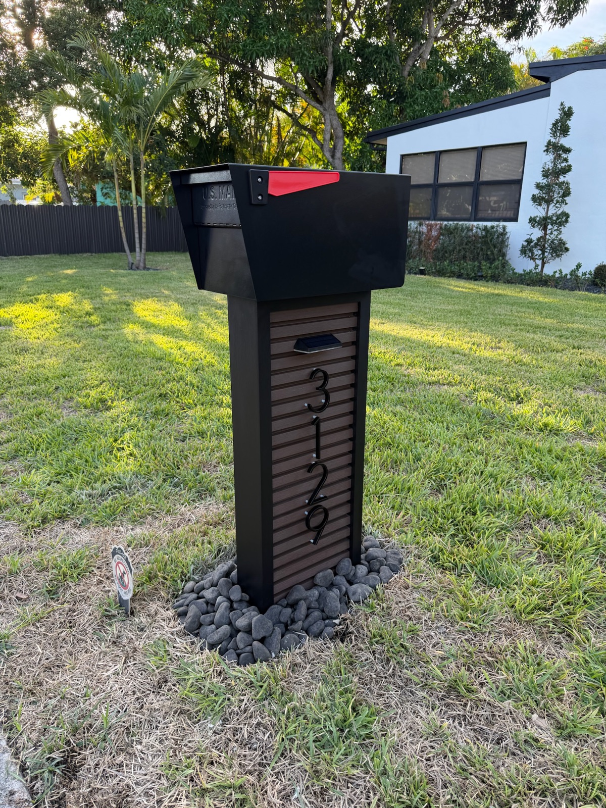A custom mailbox and post set at the curb with a finished rock bed at the base