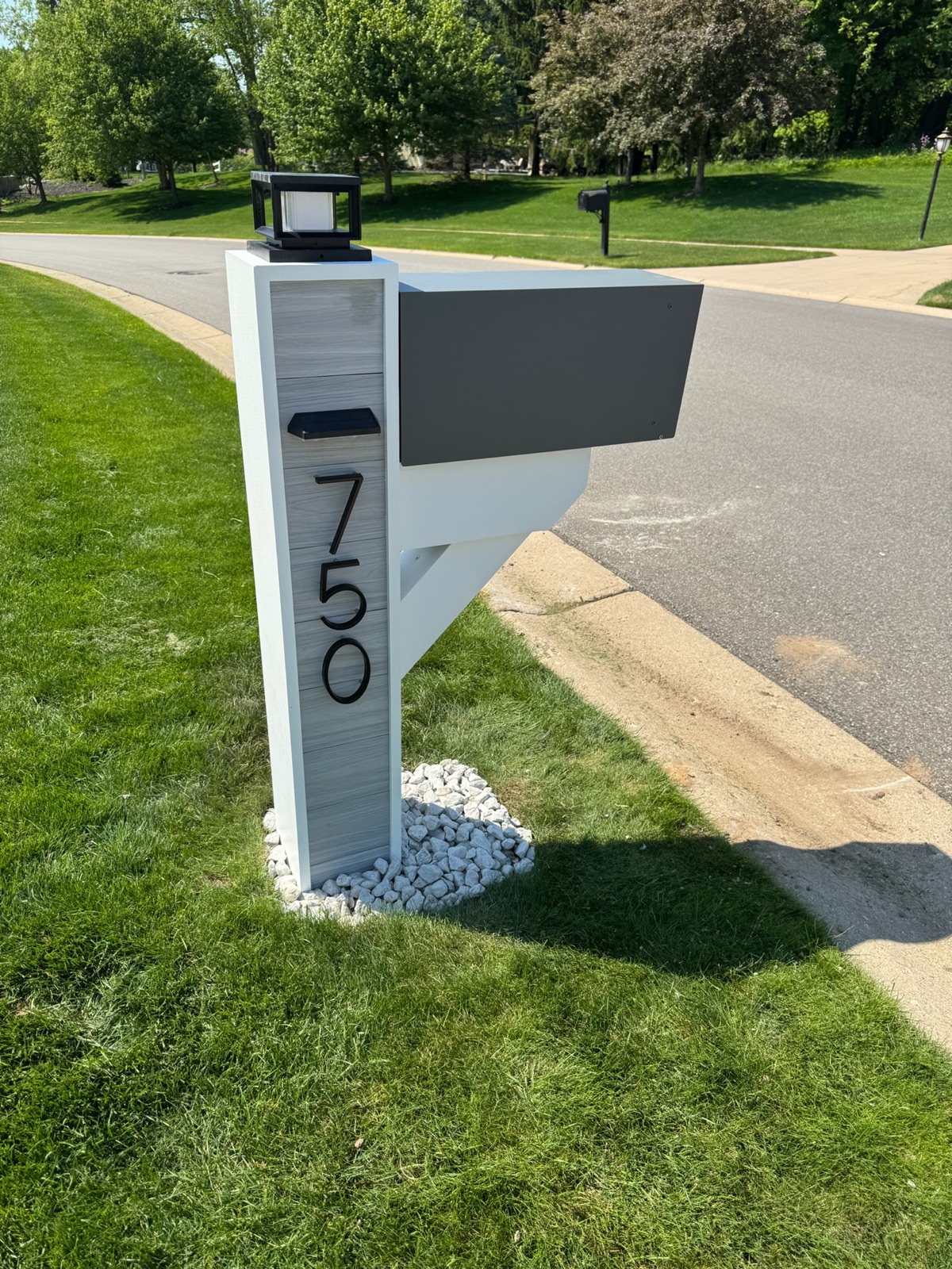A row of community mailbox posts along a residential street, several leaning at the base