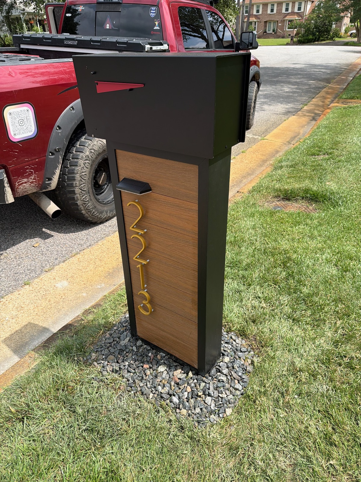 A custom community mailbox set at the curb with a finished base and matching house numbers