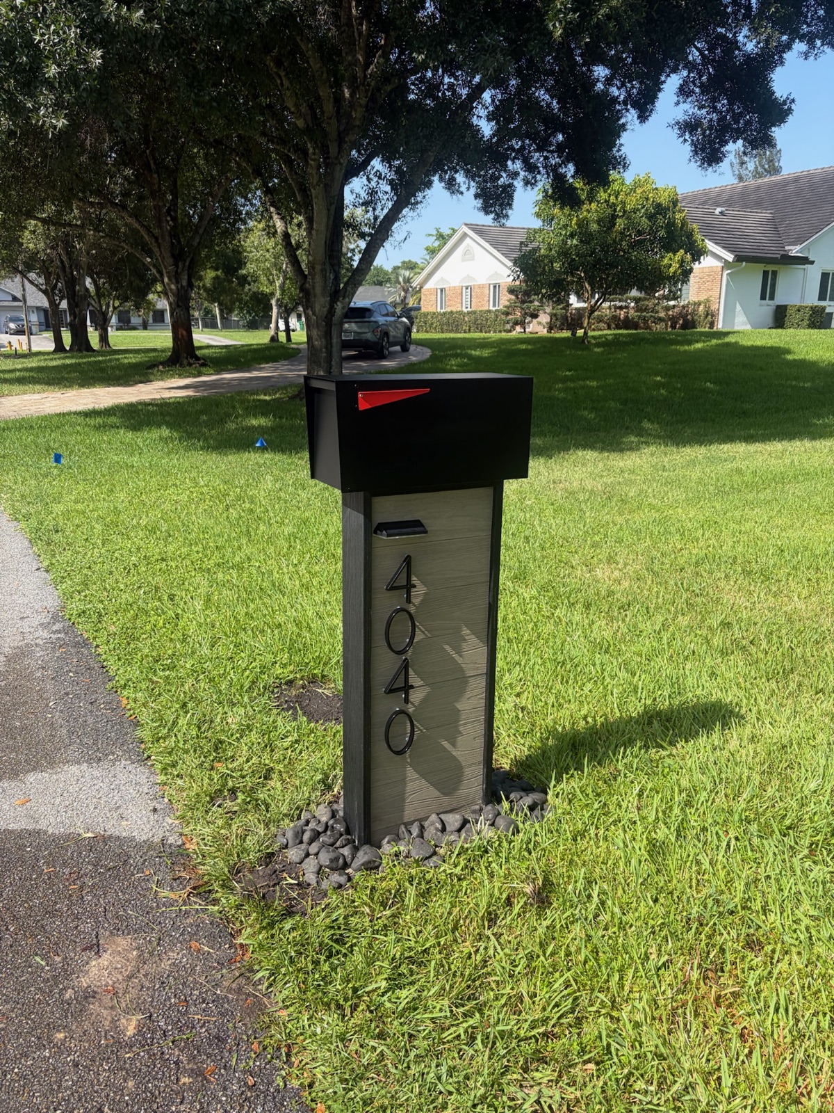 A custom post-mount mailbox set at the curb beside a home's front walkway