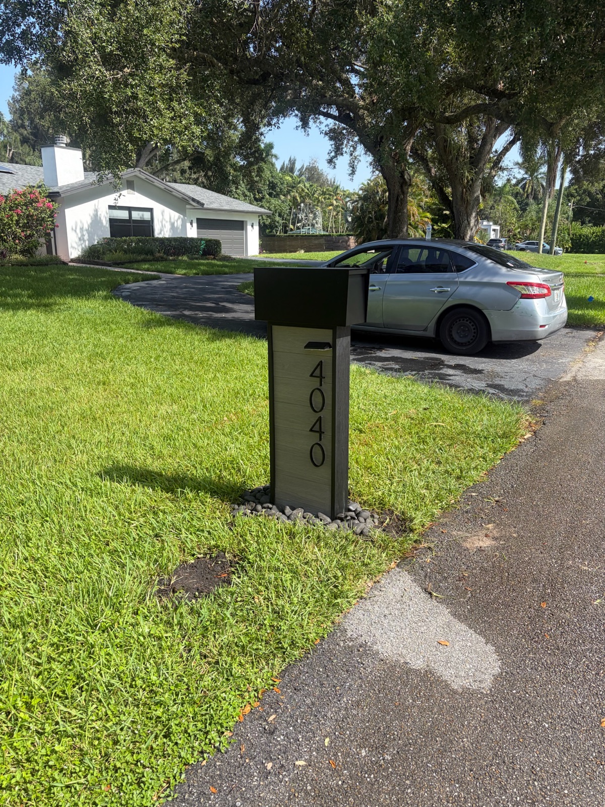 A custom wall-mount mailbox beside a home's front entry next to the door and light fixture