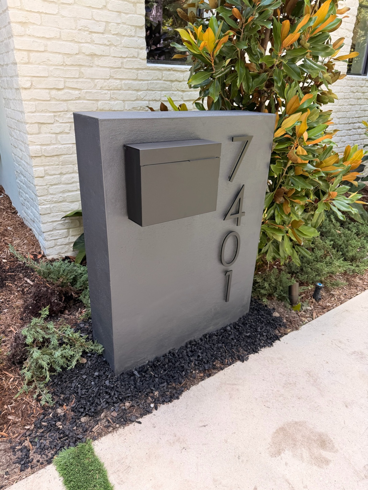 A crew setting a new mailbox post in concrete at the curb of a residential street